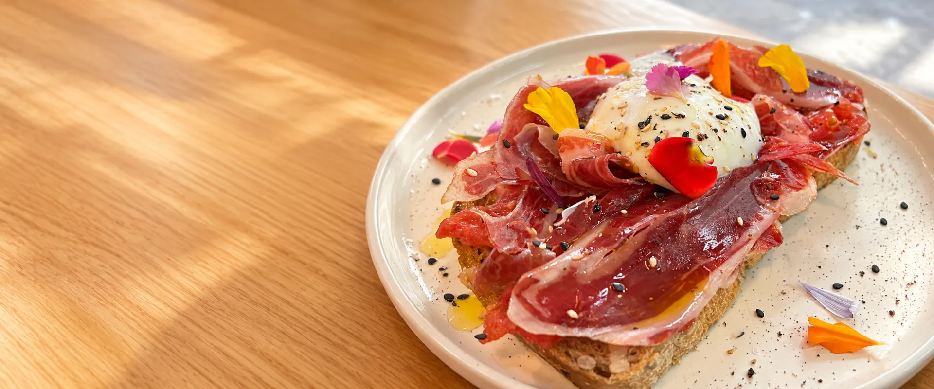 Tostada de jamón con huevo y flores comestibles en Petit Café, Gros, Donostia